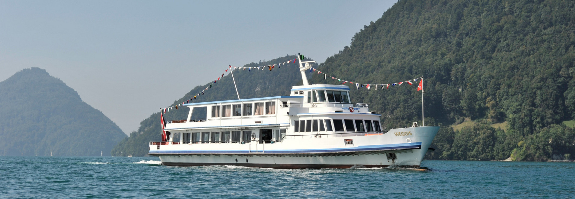 The motor vessel Weggis cruises on Lake Lucerne in sunny weather.
